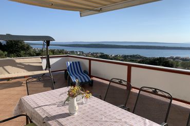 terrace with sea view, table and chairs, awning and deck chairs